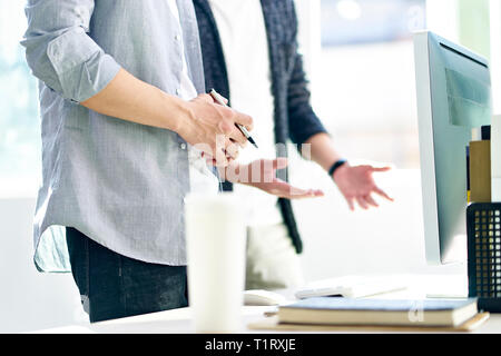 asian corporate executives standing in front of computer discussing business plans in modern office. Stock Photo