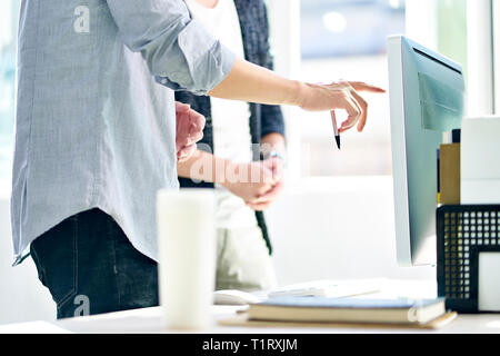 asian corporate executives standing in front of computer discussing business plans in modern office. Stock Photo