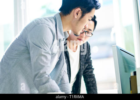two young asian business people working together in office discussing business. Stock Photo
