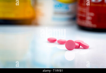 Round pink tablets pill on blurred background of drug bottle. Painkiller medicine. Drug use for treatment migraine headache. Pharmacy products. Pharma Stock Photo
