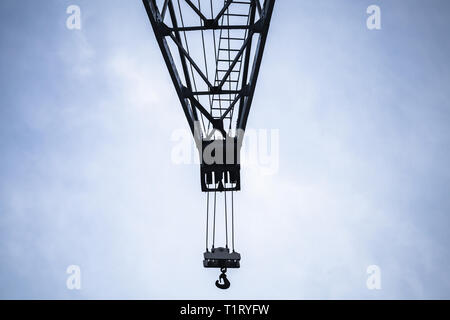 Crane boom with hook is under blue sky Stock Photo