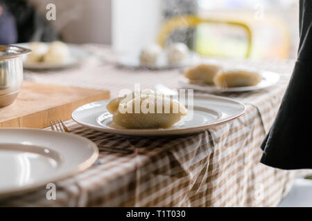 Making of Cepelinai - Zeppelins is national Lithuanian dish. Serving hot zeppelins on a plate at home Stock Photo