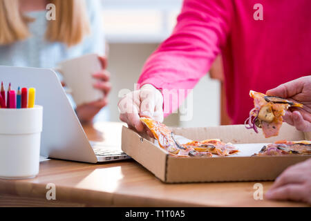 Happy business People Having Meeting And Eating Pizza in office.  Three young cheerful colleagues having lunch together at work. Creative team around Stock Photo