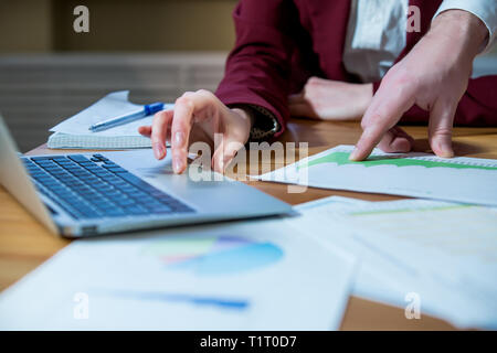 Business partners discussing documents and ideas at meeting in office. Sharing experience with colleague. Man and woman in suits working together Stock Photo
