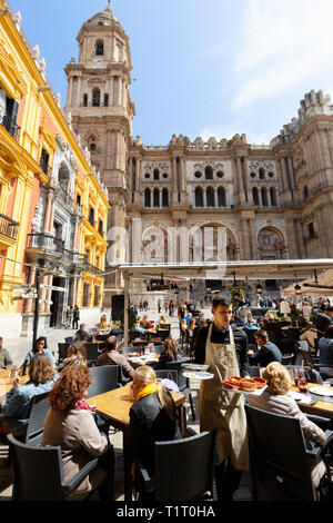 Malaga Spain; Tourists sitting at La Malaguena cafe overlooking Malaga Cathedral, Plaza del Bispo, Malaga Old Town, Andalucia Spain Stock Photo