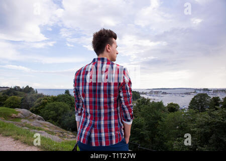 Man in stylish suit looking forward to the sea horizon. Standing on the top of the rock. Finland, Helsinki, islands. Stock Photo