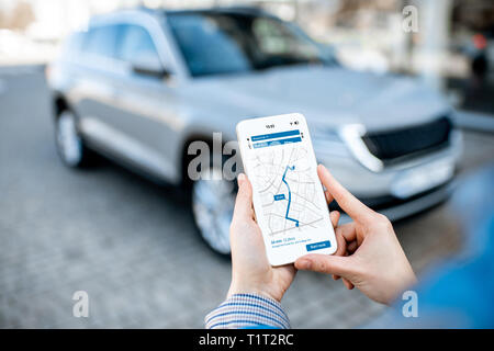 Woman using smart phone with navigation app, close-up view with modern car on the background Stock Photo
