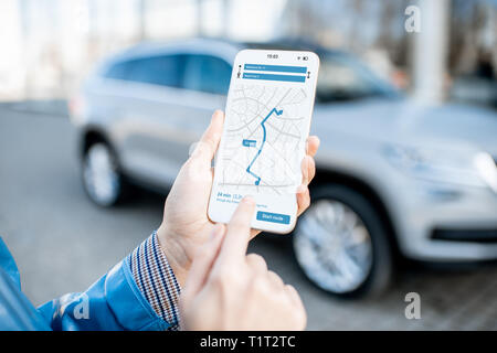 Woman using smart phone with navigation app, close-up view with modern car on the background Stock Photo