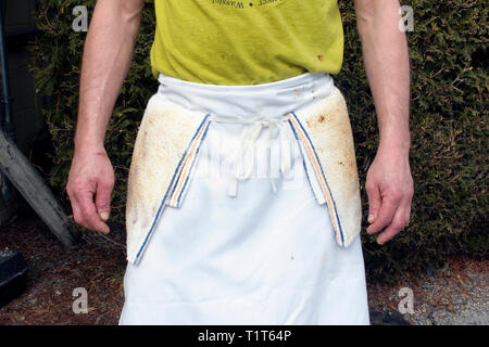 A  kitchen worker wearing a dirty white apron standing outside of his diner Stock Photo