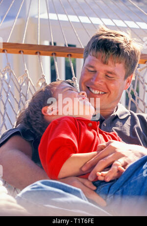 Father and son relax in a hammock Stock Photo