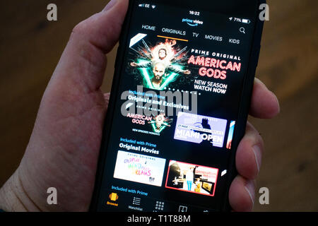 Using a mobile phone to browse Amazon Prime  Video movie streaming app Stock Photo