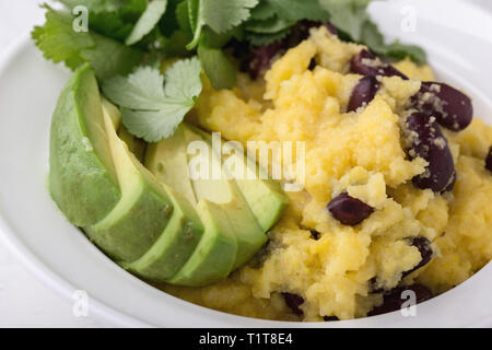 Healthy vegan brunch bowl with  grits, black beans,  avocado, topped fresh cilantro, Mexican style dish, close up, selective focus Stock Photo