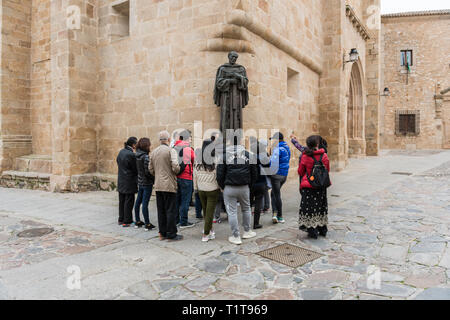 Asian tourists in front of the statue of San Pedro de Alcantara located at the gates of the concathedral of Santa Maria Stock Photo