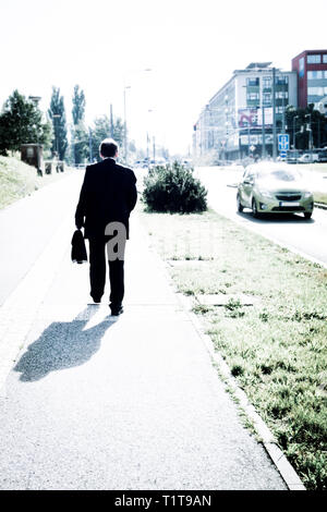 man in suit with a briefcase walking along a sidewalk in a city street Stock Photo
