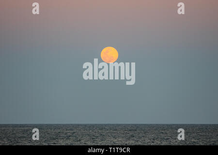 The full moon rises over the Caribbean Sea at sunset. Stock Photo