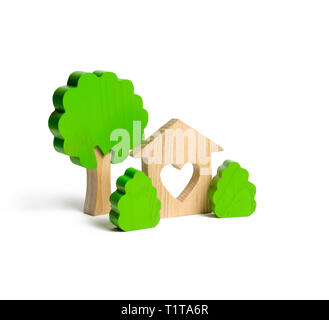 A house with a heart and wooden figures of trees with bushes on an isolated background. The concept of a love nest. Acquisition of affordable housing  Stock Photo