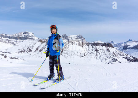 Young skier standing at the edge of a mountain range in Lake Louise at the Canadian Rockies of Alberta, Canada. Stock Photo