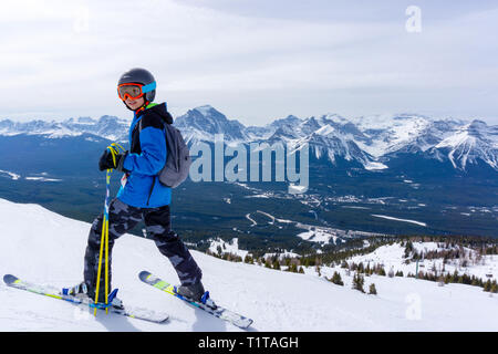 Young skier standing at the edge of a mountain range in Lake Louise at the Canadian Rockies of Alberta, Canada. Stock Photo