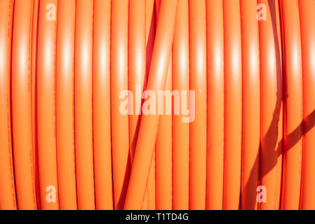 A roll of orange protective plastic insulation for a high-tension wire from a telecommunications company. Stock Photo