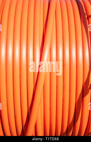 A roll of orange protective plastic insulation for a high-tension wire from a telecommunications company. Stock Photo