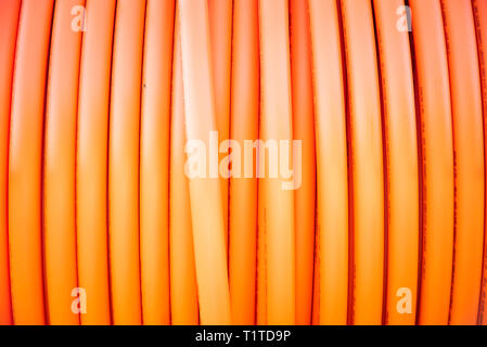 A roll of orange protective plastic insulation for a high-tension wire from a telecommunications company. Stock Photo