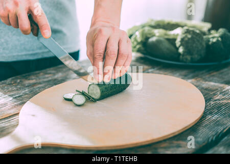 Man cutting cucumbers to make a healthy tasty salad Stock Photo