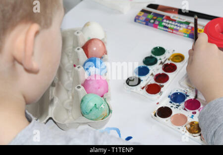A child paints eggs with a brush. Paint the eggs for Easter. Marble colored eggs. Pastel shades. Easter eggs. Stock Photo