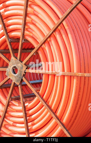 A roll of orange protective plastic insulation for a high-tension wire from a telecommunications company. Stock Photo