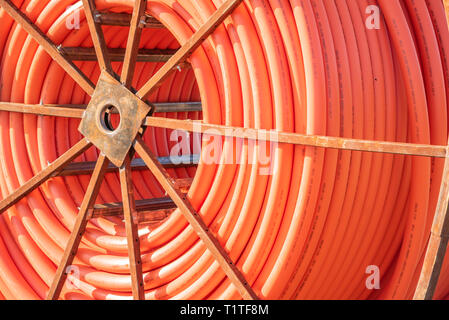 A roll of orange protective plastic insulation for a high-tension wire from a telecommunications company. Stock Photo