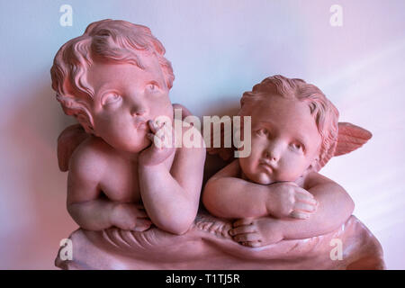 Two pretty Cherubs leaning on their arms and looking out as they lean on a sea shell Stock Photo