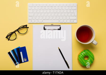 Keyboard, cup of tea, credit cards, paper and pen on yellow background. Ready for shopping. Copy space. Free space. Stock Photo