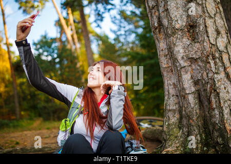 Photo of happy woman photographing herself in autumnal forest Stock Photo