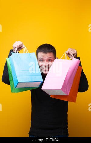 Image of happy man with shopping bags on orange background Stock Photo