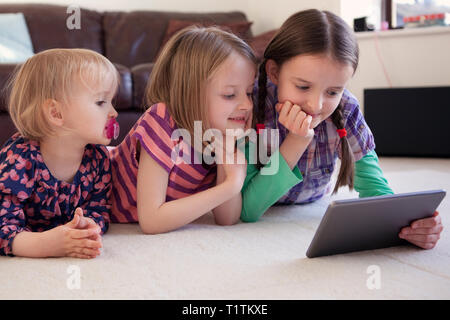 Three children using a tablet device together Stock Photo