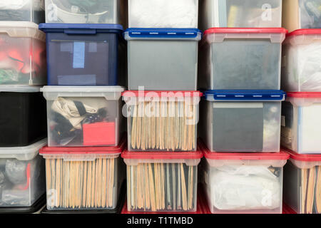 Stacked plastic file storage boxes with folders, binders and miscellaneous items. Stock Photo