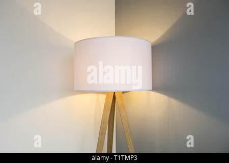 floor lamp standing near white grey wall with big lamp shade modern design, symmetrical light background texture Stock Photo