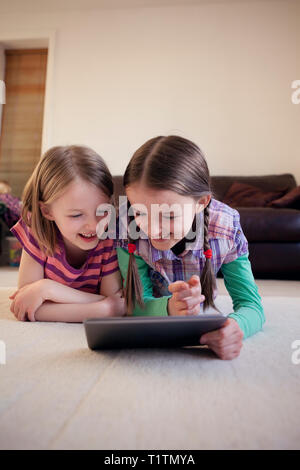 Two happy children using a tablet device together Stock Photo