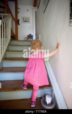 Toddler climbing wooden staircase in a house Stock Photo