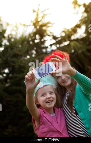 Two smiling children using a smartphone to take a selfie Stock Photo