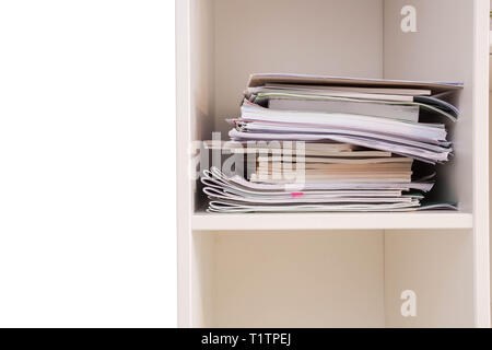 Pile of documents on a wooden shelf stack up high waiting to be managed, closet closeup Stock Photo