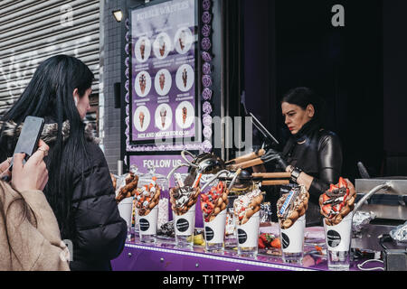 London, UK - March 23, 2019: Customers buying bubble waffles at a stall inside Camden Market, London. Started with 16 stalls in 1974, Camden Market is Stock Photo