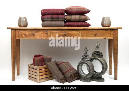 Sideboard style wooden table with cushions and throws on a white background Stock Photo