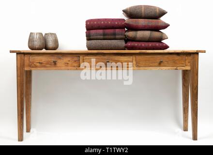 Sideboard style wooden table with cushions, throws and ornaments on a white background Stock Photo