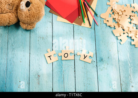 Stationery and word TOY made of letters, mock up and pieces of puzzles on the background of wooden table. Business, education, school, strategy, creat Stock Photo