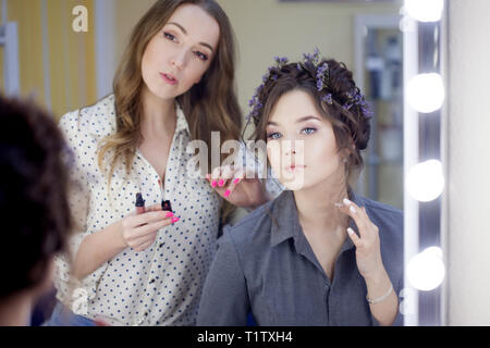 Stylist makeup artist doing makeup and hair in a beauty salon. Professional make-up, master of image creation. Stock Photo