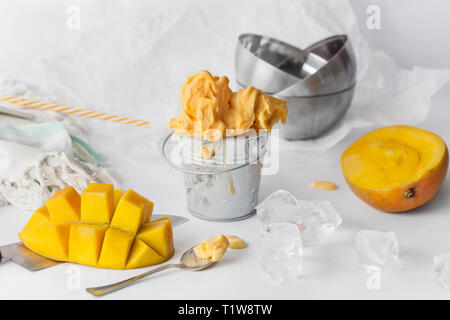 Mango ice cream in a metal mini bucket decorated with sliced mango cubes on white background Stock Photo