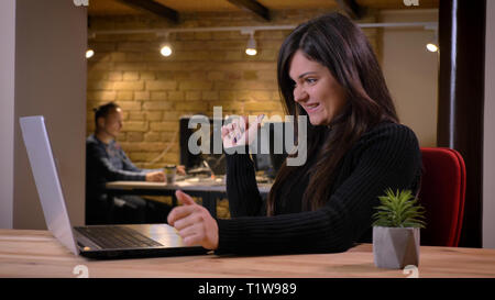Portrait of middle-aged overweight businesswoman working with laptop and smiling for success on office background. Stock Photo