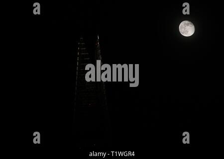 Worm moon seen over skyscraper glass hotel in London, England Stock Photo