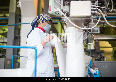 14 october 2014.Ukraine.Kyiv. The woman of average years in a white dressing gown works on a conveyor at factory of times of the Soviet, manual skills Stock Photo
