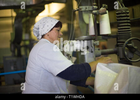 14 october 2014.Ukraine.Kyiv. The woman of average years in a white dressing gown works on a conveyor at factory of times of the Soviet, manual skills Stock Photo